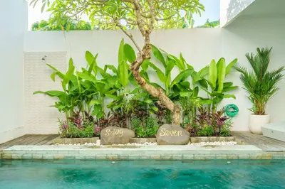 a swimming pool with a tree and signs that say singapore at Selog Seven in Seminyak
