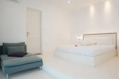 a white bedroom with a bed and a chair at PEKO VILLA - 1 BED - SEMINYAK in Seminyak