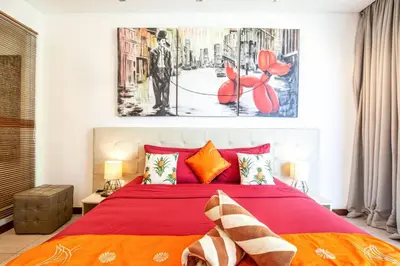 a bedroom with a red bed and a painting on the wall at Villa Nikko I - 4Br Villa in Central Seminyak, Steps to Cafés & Shops in Seminyak