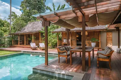 a house with a pool and a deck with a table and chairs at Villa Amore - Elegant 4-br Villa close to the beach in Canggu