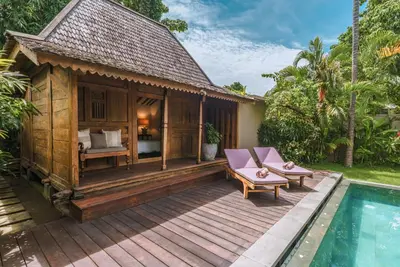 a wooden deck with a bed and a swimming pool at Villa Amore - Elegant 4-br Villa close to the beach in Canggu