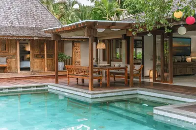 an outdoor dining area with a table and a pool at Villa Amore - Elegant 4-br Villa close to the beach in Canggu