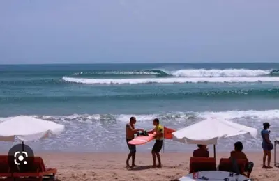 a group of people standing on a beach with a surfboard at Wyanna Villa LEGIAN in Legian