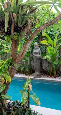 a statue next to a swimming pool in a garden at Villa Tepi Sungai - 6BR Luxury Private Pool Villa - Seminyak Sleeps 14 in Legian