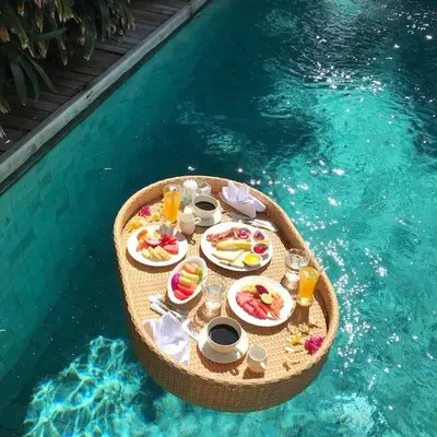a table with food and drinks in a swimming pool at Wahyu wonderful private honeymoon joglo in Seminyak