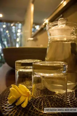 a yellow flower sitting next to two glass jars on a table at Wahyu wonderful 2Bd villa with huge garden and large pool in Seminyak