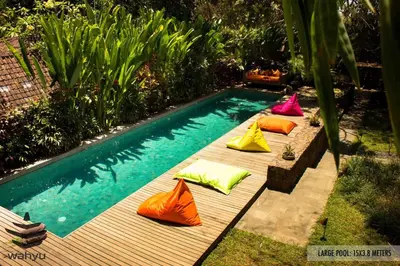 a row of colorful pillows sitting next to a swimming pool at Wahyu wonderful 2Bd villa with huge garden and large pool in Seminyak