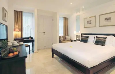 a bedroom with a large bed and a living room at The Colony Hotel Bali in Seminyak