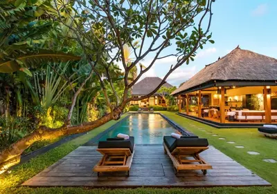 a pool with two lounge chairs next to a house at Villa Wolfe by Villa Finder in Seminyak