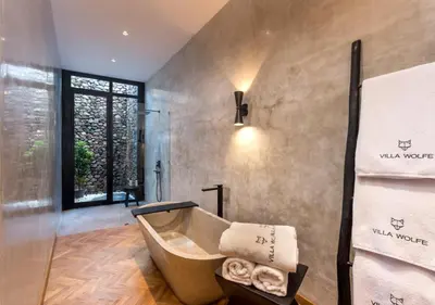 a bathroom with a bath tub and a window at Villa Wolfe by Villa Finder in Seminyak