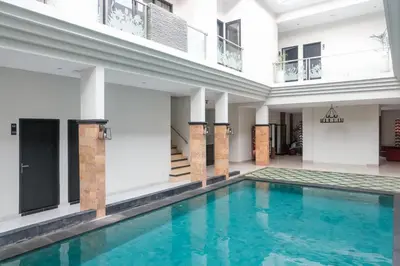 an indoor pool with blue water in a building at Guyana Hotel in Kuta