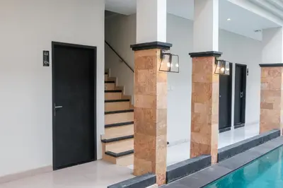 a hallway with a black door and stairs next to a pool at Guyana Hotel in Kuta