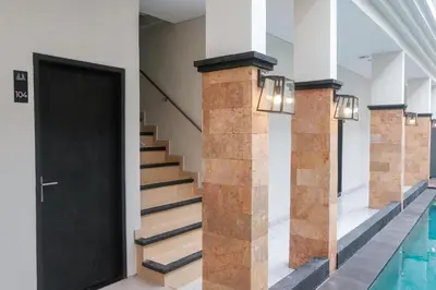 a hallway with a black door and stairs at Guyana Hotel in Kuta