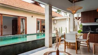 a villa with a swimming pool and a dining area at Cosy and Cheerful 2 Bedroom villa 5mins to Finns in Canggu