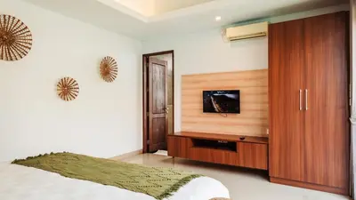 a bedroom with a bed and a wooden cabinet at Cosy and Cheerful 2 Bedroom villa 5mins to Finns in Canggu