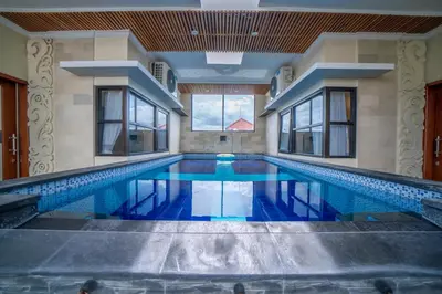 a swimming pool in a building with a large window at Padma Lodge Legian in Seminyak
