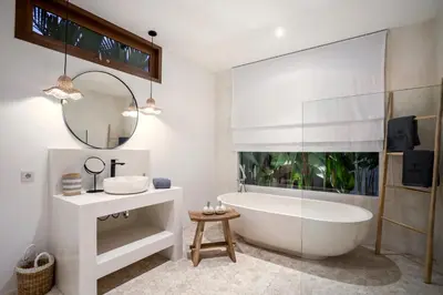 a bathroom with a tub and a sink and a mirror at Villa Cocotier by Alfred in Bali in Seminyak