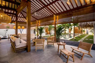 an outdoor living room with a wooden pergola at Villa Cocotier by Alfred in Bali in Seminyak