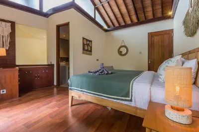 a bedroom with a bed and a wooden floor at Ajiorqo Villa in Seminyak