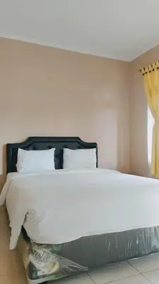 a bedroom with a large white bed and a window at PURNAMA HOUSE KUTA in Kuta