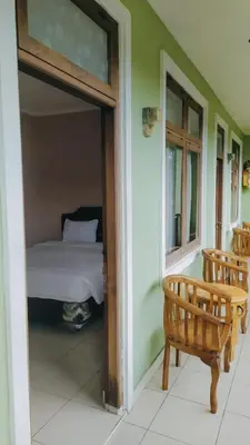 a bedroom with a bed and a bench on a porch at PURNAMA HOUSE KUTA in Kuta
