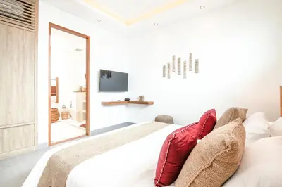 a white bedroom with a large bed with red pillows at Exquisite 4Bd Gem, 5min to Finns Coastal Vibe in Canggu