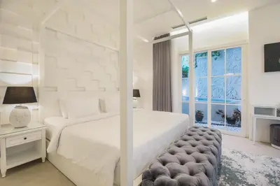a white bedroom with a large bed and a window at Villa Rose in Seminyak