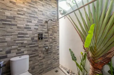 a bathroom with a shower with a toilet and a plant at PROMO Modern Seminyak Pvt Villa with Pool and Parking in Seminyak