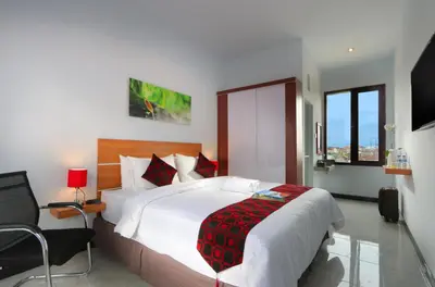 a bedroom with a large bed and a chair and window at Valomia Guest House in Kerobokan