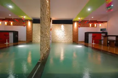 an empty swimming pool in a room with a bar at Valomia Guest House in Kerobokan