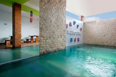 a pool of water in a room with a brick wall at Valomia Guest House in Kerobokan