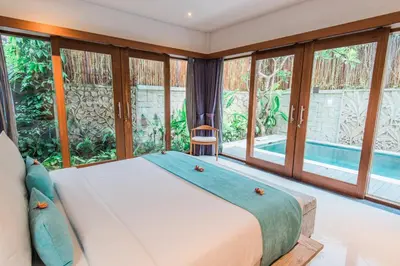 a bedroom with a large bed and large windows at Lacasa3 Villa Legian With Butler in Legian