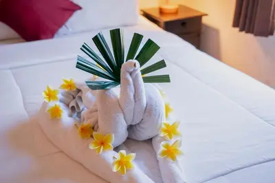 a towel animal sitting on a bed with flowers at Umah Kita in Seminyak