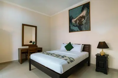 a bedroom with a bed and a table and a mirror at Umah Kita in Seminyak