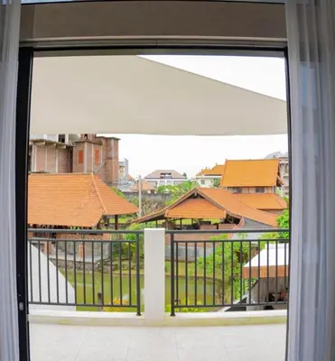 an open door to a balcony with a view of buildings at Berawa Homestay in Canggu