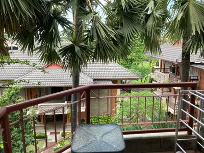 a chair sitting on a balcony with palm trees at Coastal Suite at Jayakarta Residence in Seminyak