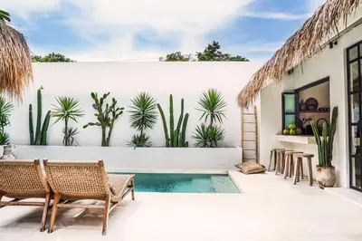 a patio with a pool and chairs and plants at Villa Obao in Seminyak