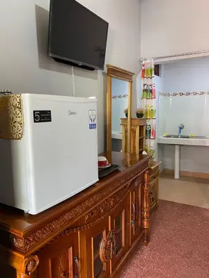 a television on top of a wooden cabinet with a refrigerator at Guest House Pondok Puspa Ayu in Kuta