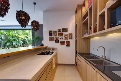 a kitchen with wooden cabinets and a sink and a window at Incredible 4BR Villa 5 mins walk to the beach in Canggu