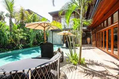 a patio with a table and umbrella next to a swimming pool at Elegant 6BR Villa, Canggu, 400m to Finns Beach in Canggu