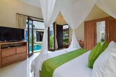 a bedroom with a large bed with a tv and a bed sqor at Villa Intan in Legian