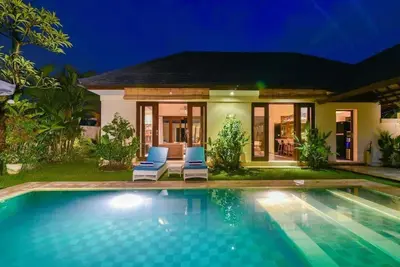 a villa with a swimming pool at night at Villa Intan in Legian