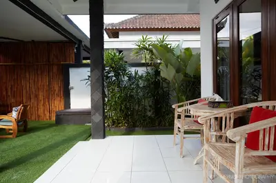 a patio with chairs and a table on a lawn at Villa Kaya in Seminyak