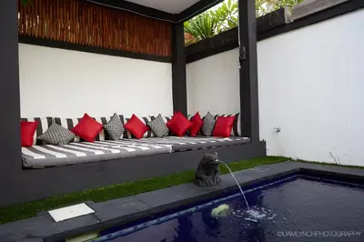 a bench with red and black pillows next to a pool at Villa Kaya in Seminyak