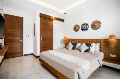 a bedroom with a large white bed and wooden doors at Villa Ara by BaliSuperHost in Seminyak