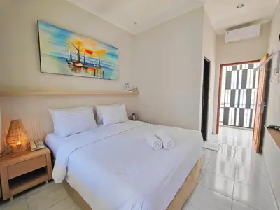 a bedroom with a white bed with two towels on it at Rabasta Enjoy Kuta in Denpasar