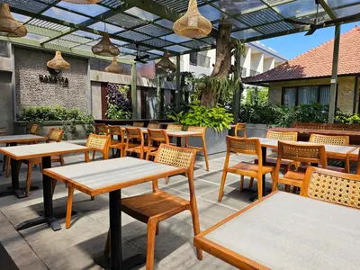 an outdoor patio with wooden tables and chairs at Rabasta Enjoy Kuta in Denpasar