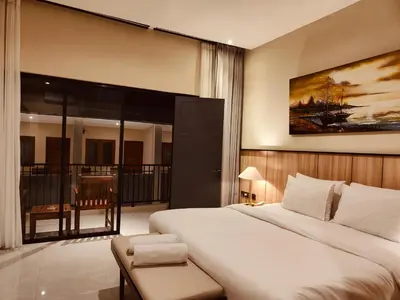 a bedroom with a large bed and a balcony at Rabasta Enjoy Kuta in Denpasar