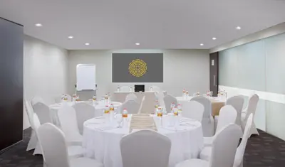 a conference room with white tables and chairs and a screen at Brits Hotel Legian in Seminyak