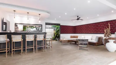 a living room with a red accent wall at Large 6-Bedroom Private Villa with Pool for Groups & Families - Umalas in Kerobokan